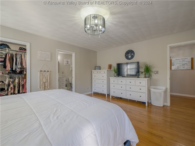 bedroom featuring hardwood / wood-style floors, a notable chandelier, ensuite bathroom, a closet, and a walk in closet