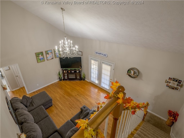 unfurnished living room with high vaulted ceiling, hardwood / wood-style floors, a notable chandelier, and a textured ceiling