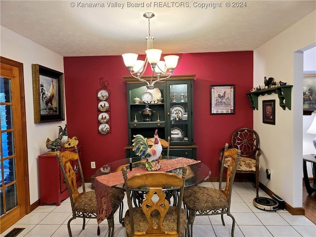 tiled dining space with a notable chandelier and a textured ceiling