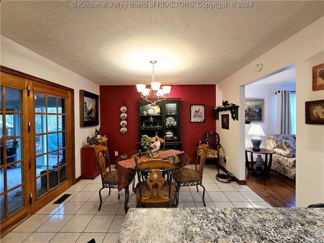 dining area featuring light tile patterned flooring, a textured ceiling, and a chandelier