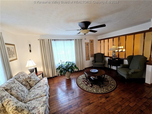 living room featuring ceiling fan, dark wood-type flooring, and a textured ceiling