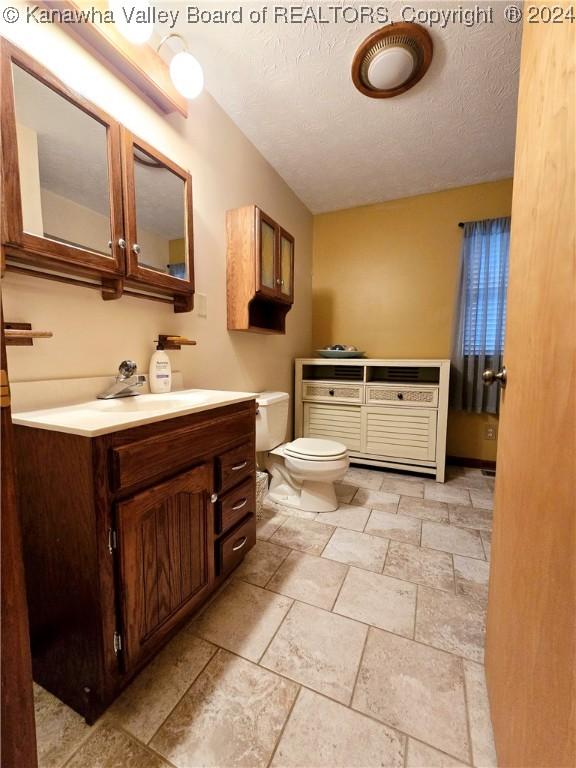 bathroom featuring vanity, toilet, and a textured ceiling