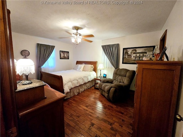 bedroom featuring dark wood-type flooring, ceiling fan, and a textured ceiling