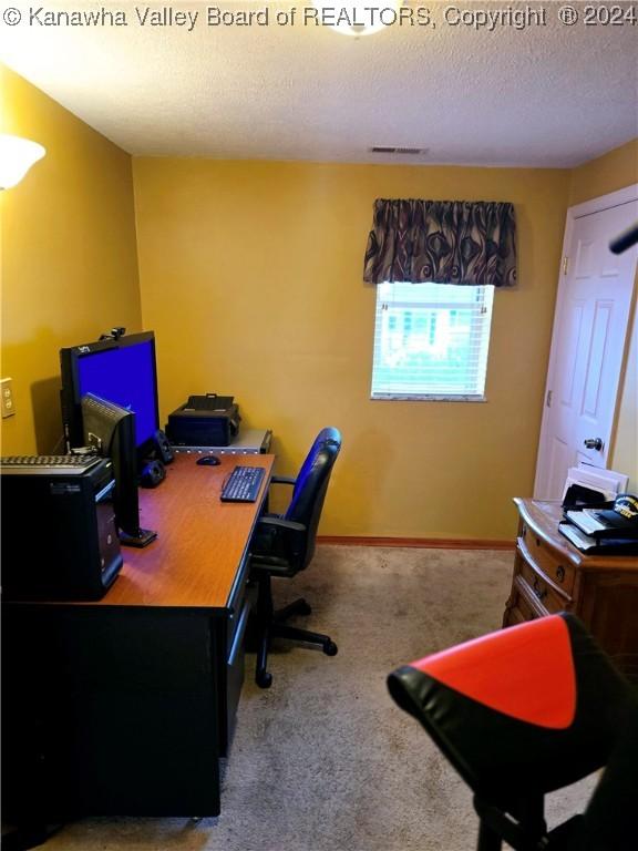 carpeted office space featuring a textured ceiling