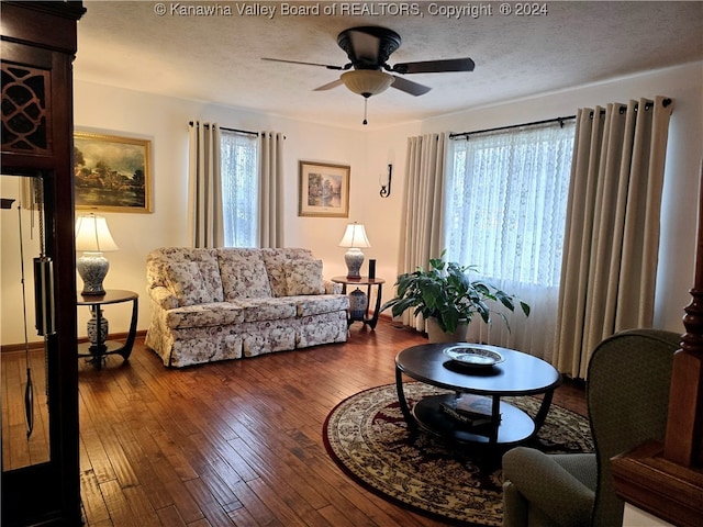 living room with ceiling fan, dark hardwood / wood-style flooring, and a textured ceiling