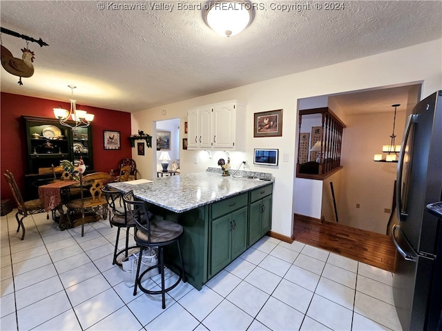 kitchen with a chandelier, light tile patterned floors, white cabinets, and a kitchen bar