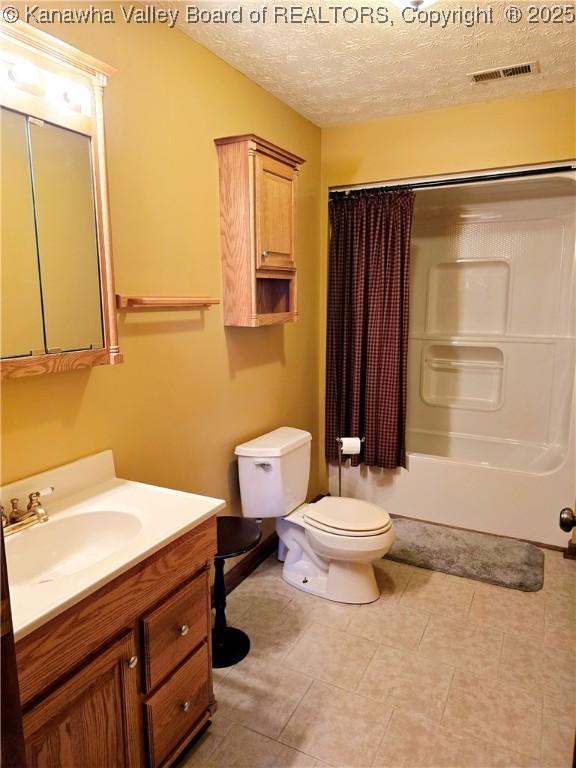 full bathroom with shower / tub combo with curtain, vanity, toilet, and a textured ceiling