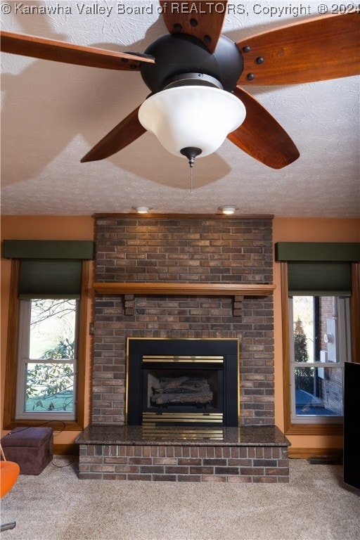 room details with a textured ceiling, carpet floors, a brick fireplace, and ceiling fan