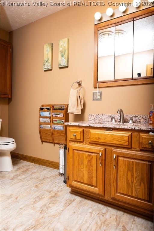 bathroom featuring vanity, toilet, and a textured ceiling