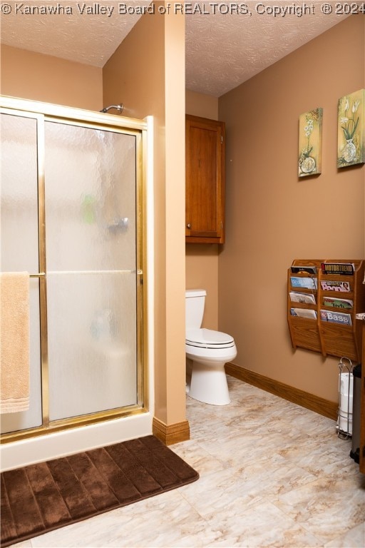 bathroom featuring toilet, a shower with door, and a textured ceiling