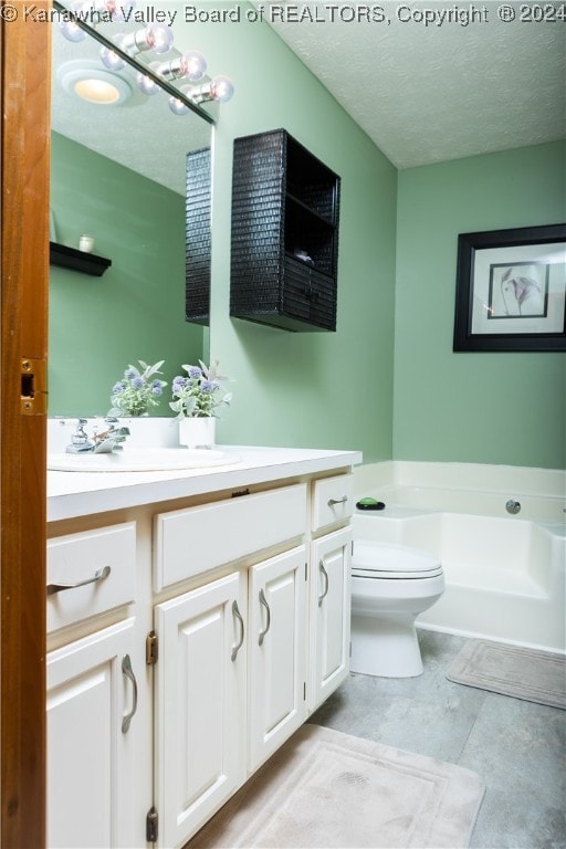 bathroom featuring a tub, vanity, a textured ceiling, and toilet