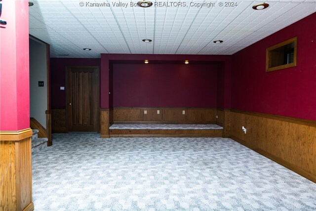 carpeted empty room featuring wooden walls