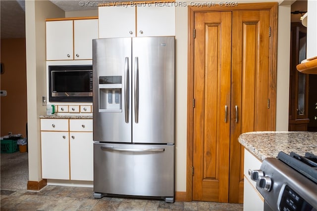 kitchen featuring white cabinets, appliances with stainless steel finishes, and light stone counters