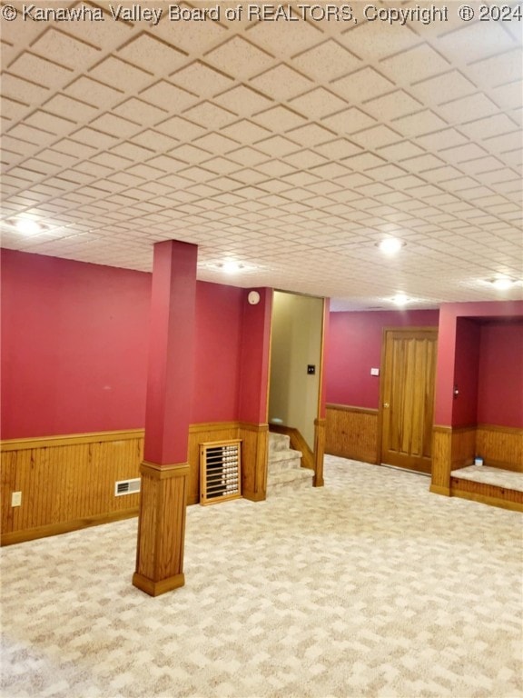 basement with carpet and wood walls