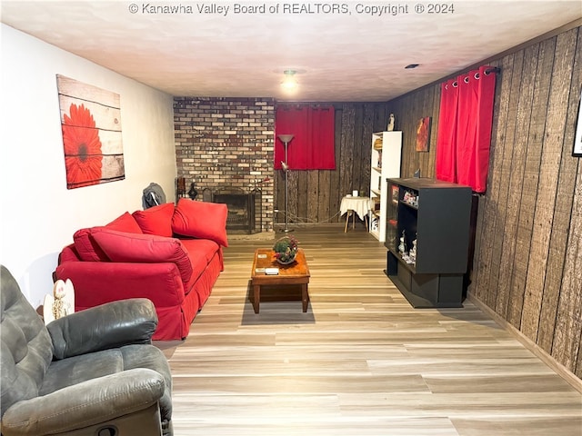 living room featuring a fireplace, wooden walls, and light hardwood / wood-style flooring