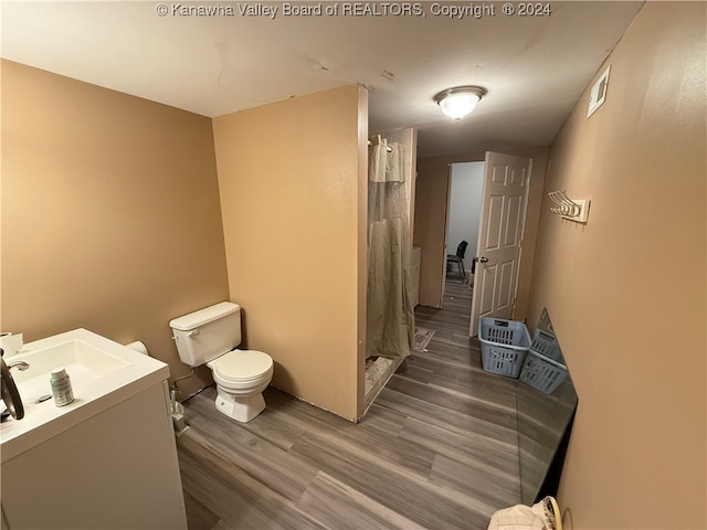 bathroom with toilet, vanity, hardwood / wood-style floors, and curtained shower