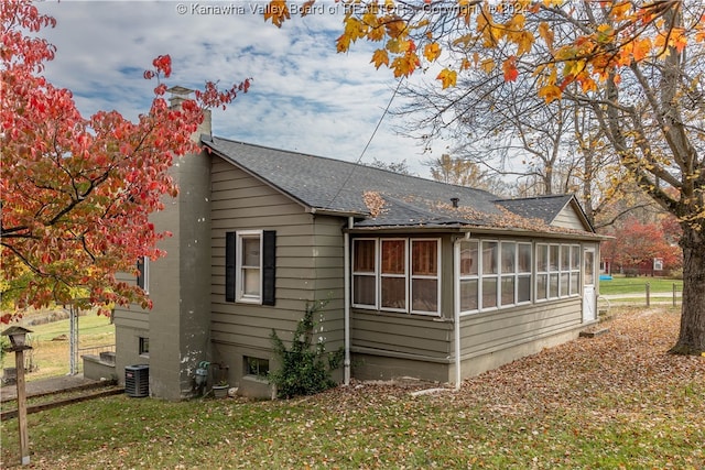 back of house featuring a lawn, central AC unit, and a sunroom