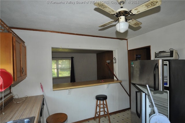 kitchen featuring kitchen peninsula, a textured ceiling, ceiling fan, crown molding, and fridge