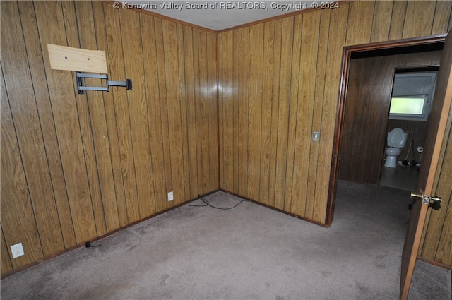 carpeted empty room with wood walls