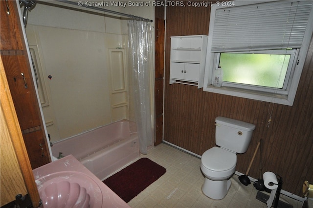 bathroom featuring toilet, wooden walls, and shower / bath combo with shower curtain