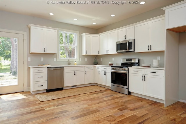 kitchen with stainless steel appliances, light hardwood / wood-style floors, white cabinetry, and plenty of natural light