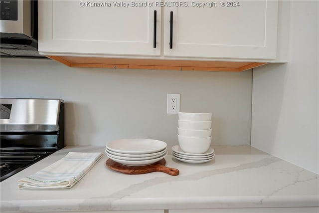 details with light stone countertops, white cabinetry, and appliances with stainless steel finishes