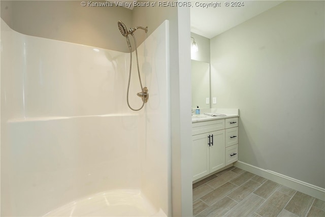 bathroom with walk in shower, wood-type flooring, and vanity