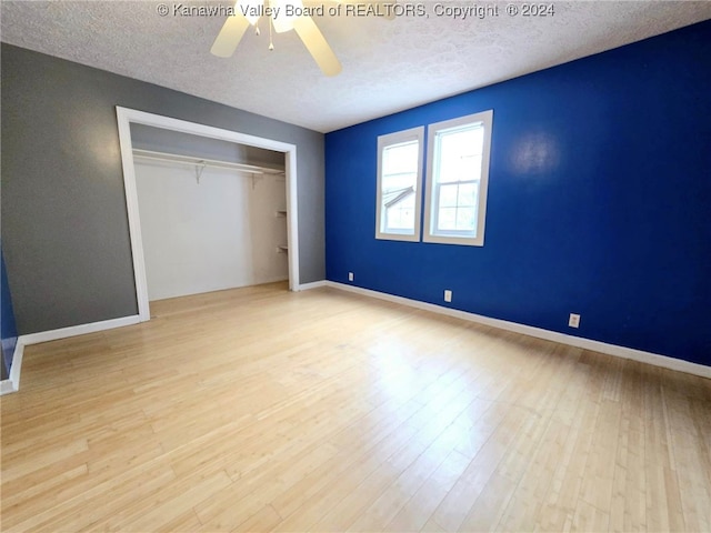 unfurnished bedroom with light hardwood / wood-style flooring, a textured ceiling, ceiling fan, and a closet