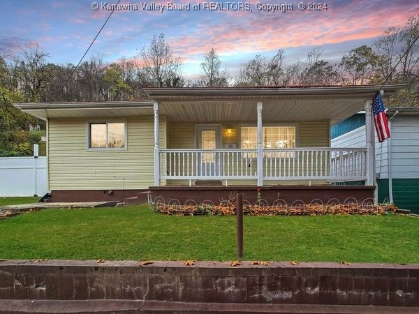 view of front of home featuring covered porch and a lawn