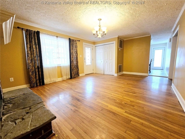 interior space with a textured ceiling, ornamental molding, and light hardwood / wood-style flooring