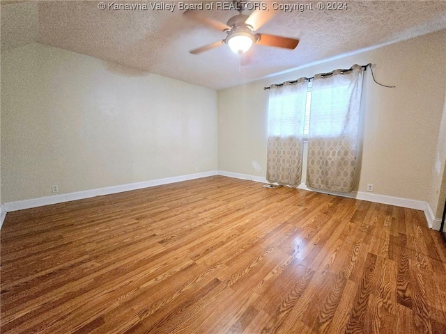 empty room featuring ceiling fan, wood-type flooring, a textured ceiling, and vaulted ceiling