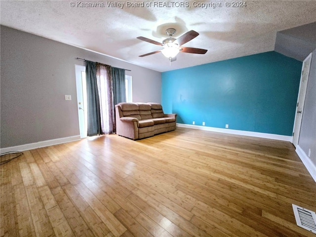 unfurnished living room featuring a textured ceiling, vaulted ceiling, ceiling fan, and light hardwood / wood-style flooring