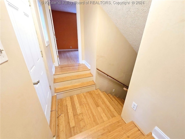 stairs with hardwood / wood-style floors and a textured ceiling