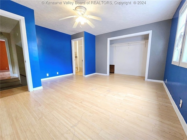 unfurnished bedroom with a textured ceiling, light wood-type flooring, ceiling fan, and a closet