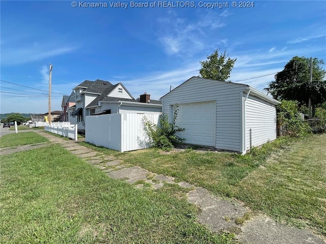 view of property exterior featuring a garage, an outdoor structure, and a lawn