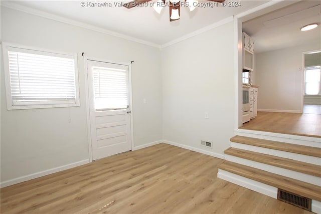 empty room featuring ornamental molding, light wood-type flooring, and ceiling fan