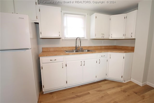 kitchen featuring white cabinets, light wood-type flooring, sink, and white fridge