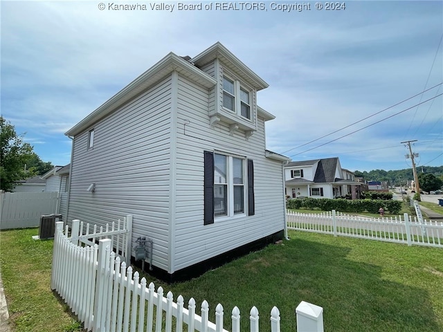 view of side of home with a lawn and central AC