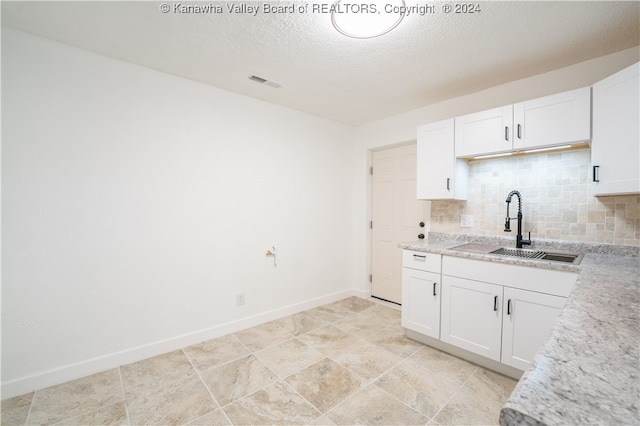 kitchen featuring white cabinets, a textured ceiling, sink, and backsplash