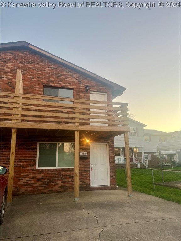 back house at dusk with a balcony and a lawn