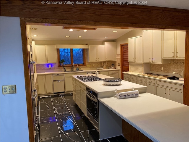 kitchen with tasteful backsplash, white cabinetry, stainless steel gas cooktop, and sink