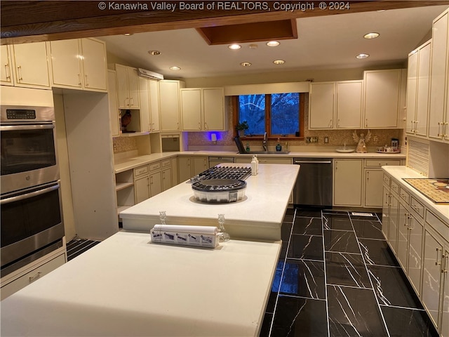 kitchen with backsplash, white cabinets, sink, appliances with stainless steel finishes, and a kitchen island