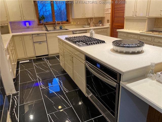 kitchen featuring sink, stainless steel gas cooktop, tasteful backsplash, cream cabinetry, and beverage cooler