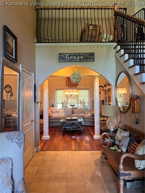 interior space with decorative columns, wood-type flooring, a high ceiling, and an inviting chandelier