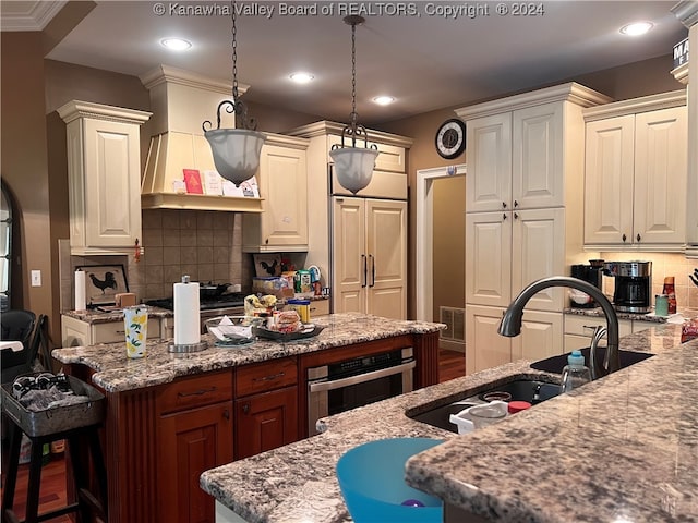 kitchen with backsplash, oven, light stone countertops, and hanging light fixtures