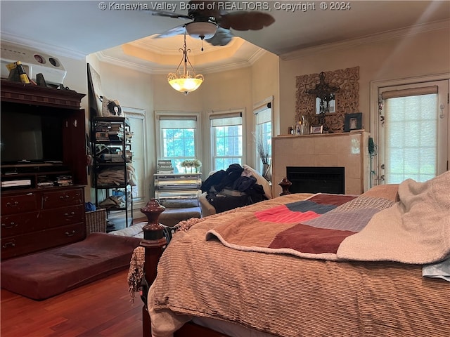 bedroom featuring a tiled fireplace, wood-type flooring, and ornamental molding