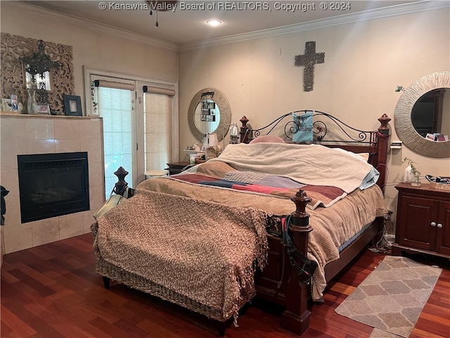 bedroom featuring a tile fireplace, dark hardwood / wood-style floors, and ornamental molding