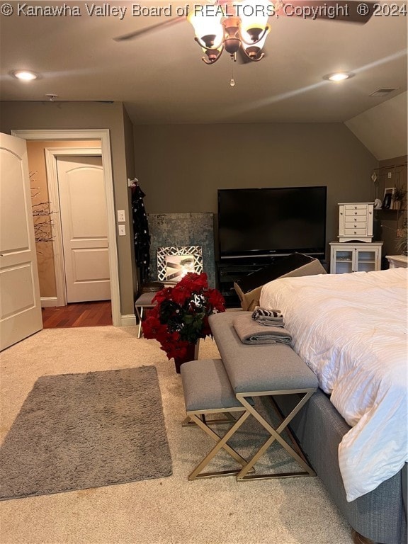 carpeted bedroom featuring ceiling fan with notable chandelier and lofted ceiling