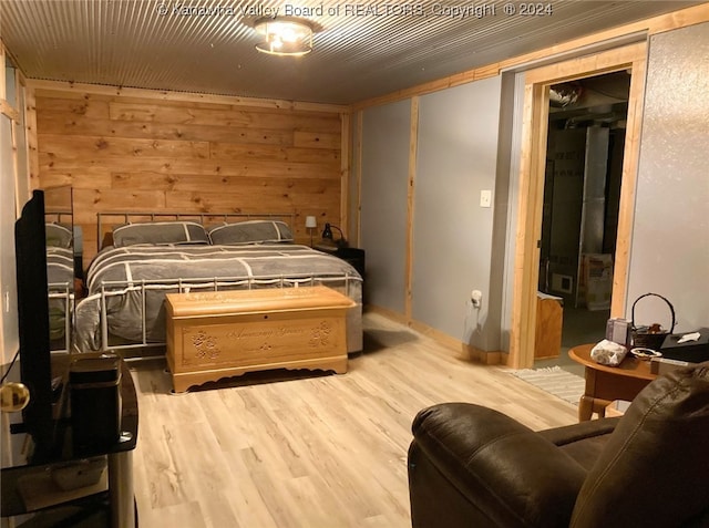 bedroom with light wood-type flooring and wooden walls