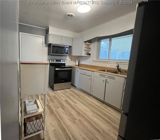 kitchen with wooden counters, appliances with stainless steel finishes, light hardwood / wood-style floors, and sink